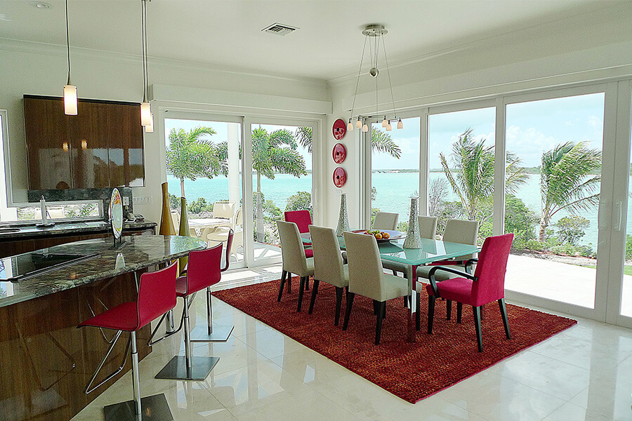 luxurious dining room with large glass windows overlooking tropical waterfront estate