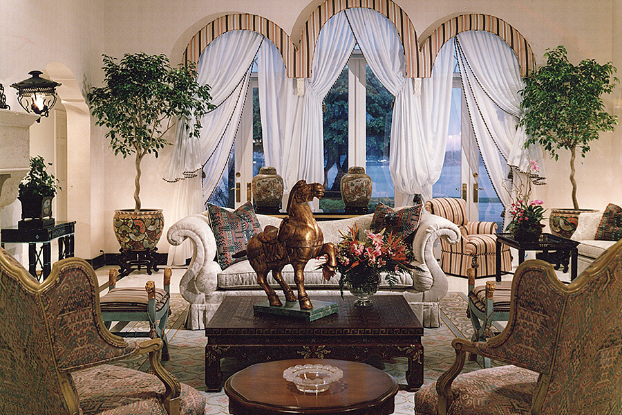 Palm Beach Estate, dining room with long glass table surrounded by eight upholstered chairs with upright backs.