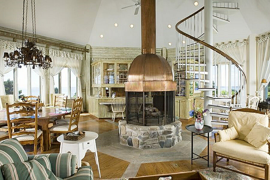 an open room design with a large fireplace in the center next to a spiral staircase.