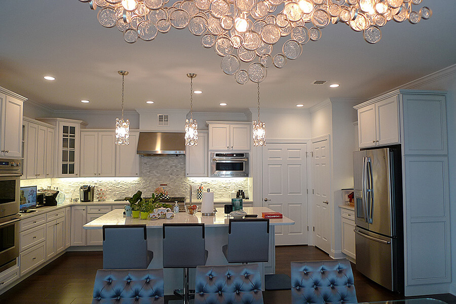 large kitchen with off white walls and cabinetry, stainless steel appliances and a island with chairs